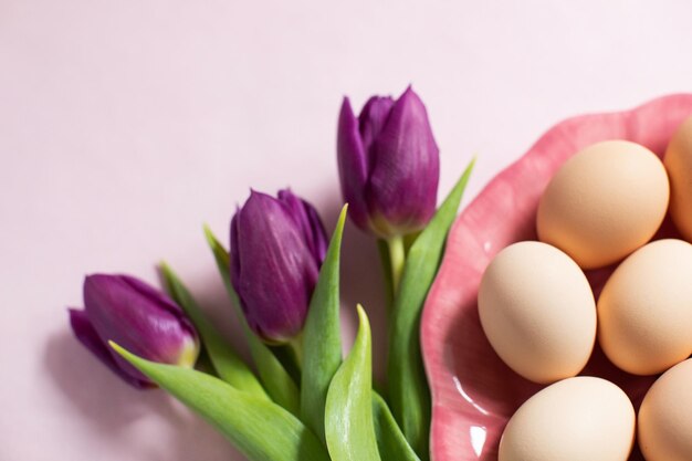 Purple tulips and easter eggs on pink background Spring time