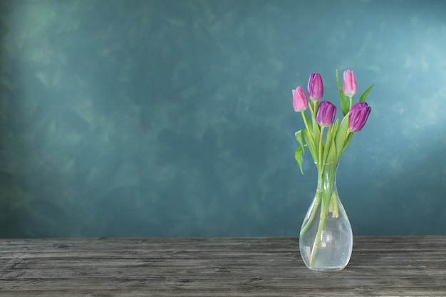 Purple tulips in glass vase on wooden table