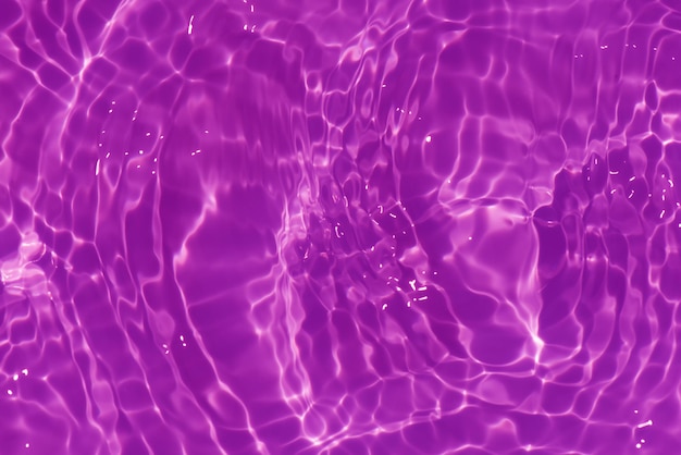 A purple water with ripples and the sun reflecting on the surface