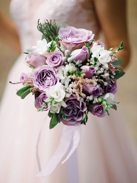 Photo purple wedding bouquet in bridal's hands.