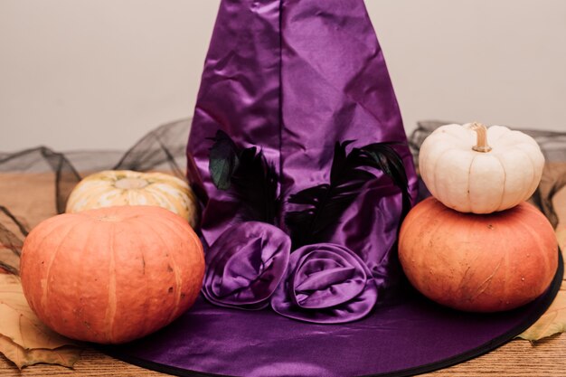 Purple witch hat lies next to pumpkins