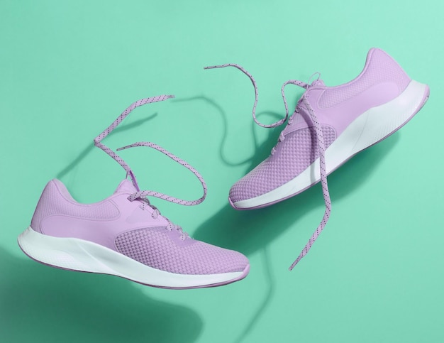 Purple women's sports sneakers with laces levitate on a green background