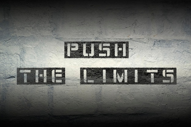 Push the limits stencil print on the grunge white brick wall