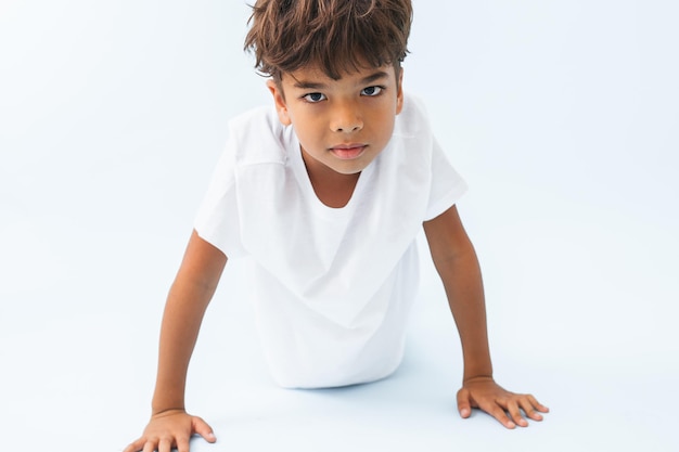 Pushing up from the floor Indian boy against bluish white background