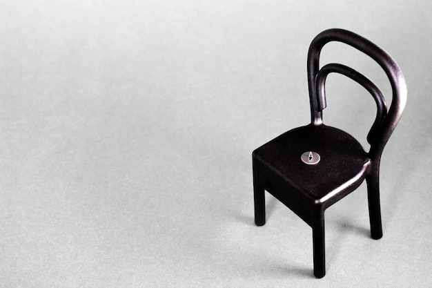 A pushpin on the black plastic chair on gray