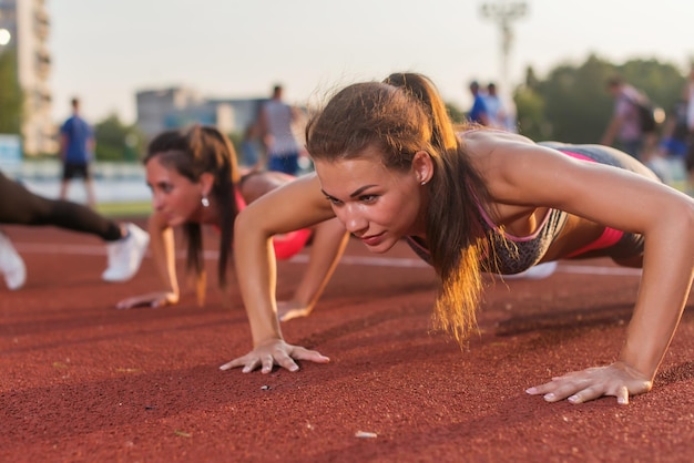 Foto pushups atleta fitness donne che si esercitano nello stadio allenamento all'aperto