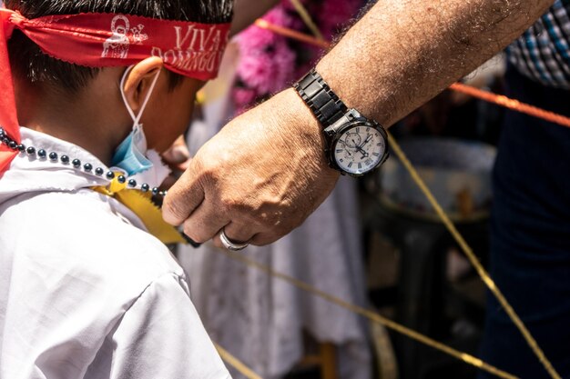 마나과 산토도밍고의 전통 축제에서 알아볼 수 없는 아이에게 전통 의상을 입은 목걸이를 걸어주는 모습