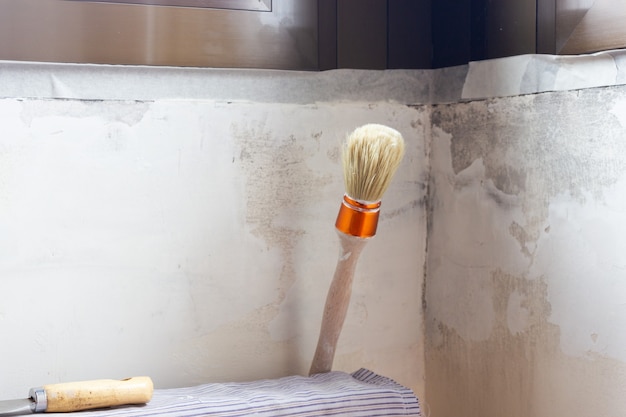 A putty knife and a paint brush on a radiator ready to fix the wall.Indoor