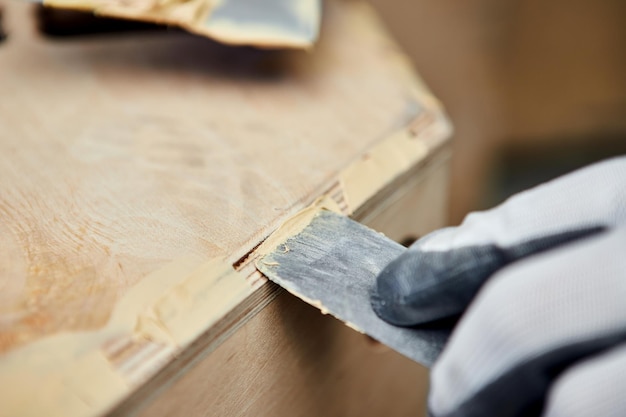 Putty of wood Manual worker spackling wooden products at the carpentry manufacturing Close up of working process