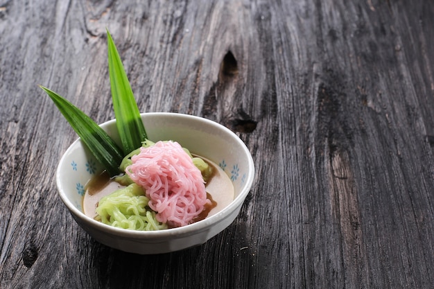 Putu Mayang of Petulo, Indonesische traditionele Javaanse snack gemaakt van rijstmeelstrengen opgerold tot een bal met kleurstof, geserveerd met kokosmelk en palmsuikersiroop.