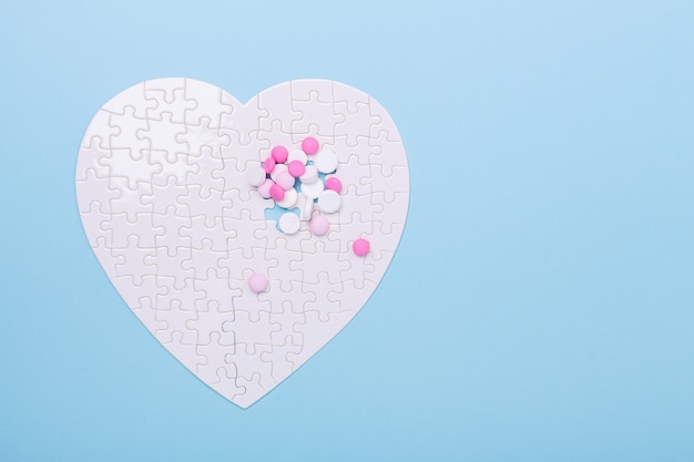 Puzzel in vorm van hart witte en roze pillen op blauw