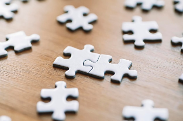 Puzzelstukjes zijn verbonden witte puzzelstukjes op een houten tafel achtergrond zakenpartner oplossing...