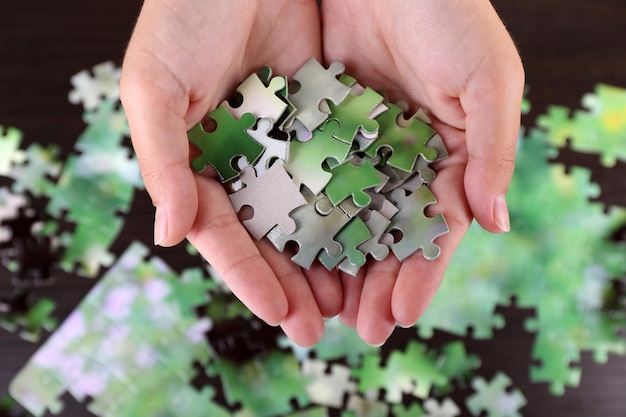 Puzzle piece in hands on wooden table background