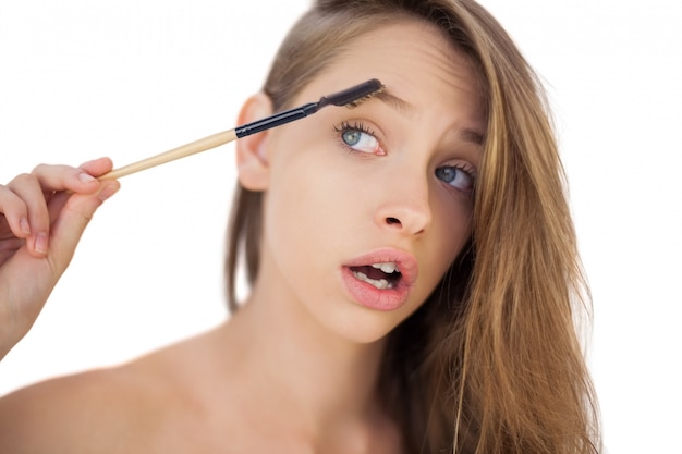 Puzzled brunette model brushing her eyebrows