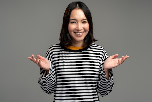 Puzzled brunette woman shrugging shoulders, confused and
uncertain with information. indoor studio shot isolated on grey
background