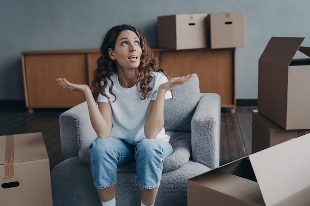 Puzzled divorced girl exclaims shrugging sitting with boxes for relocation Divorce hard moving day