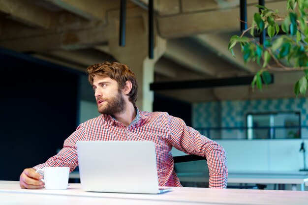 Puzzled thoughtful businessman sitting at his working table in an office. Business concept