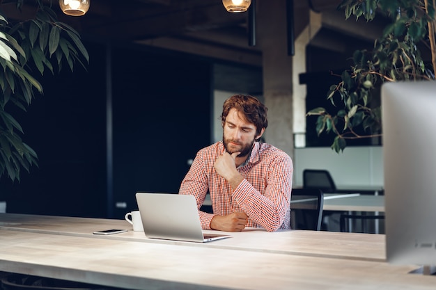 Photo puzzled thoughtful businessman sitting at his working table in an office. business concept