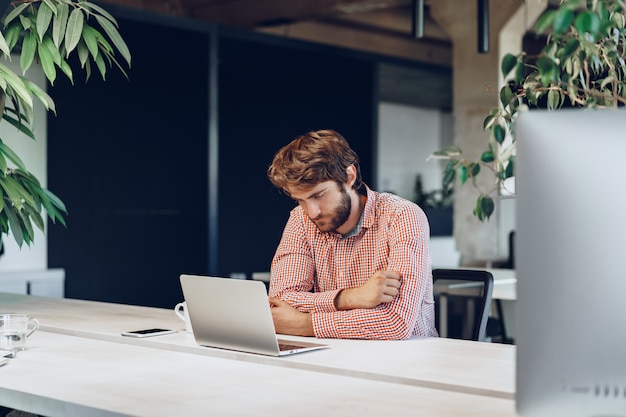 Puzzled thoughtful businessman sitting at his working table in an office