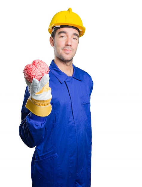 Puzzled workman holding a brain on white background