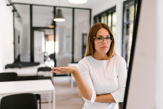 Puzzled young businesswoman looking at flipchart.