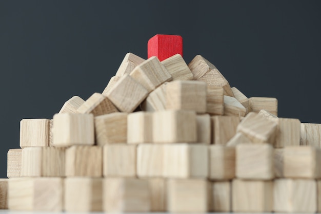 Пирамида из бежевых кубиков сверху и единичный красный на столе индивидуальный подход к каждому клиенту.