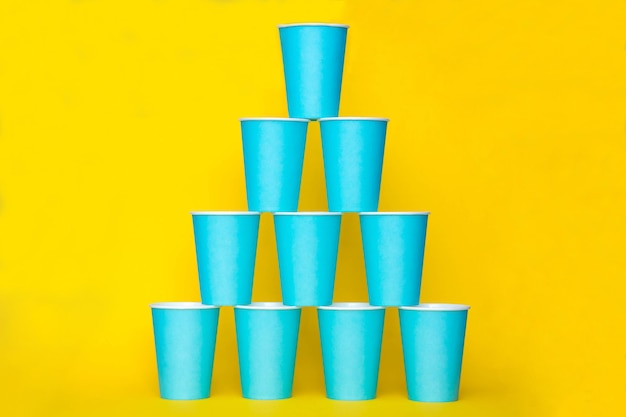 Piramide di bicchieri usa e getta di carta blu su sfondo giallo