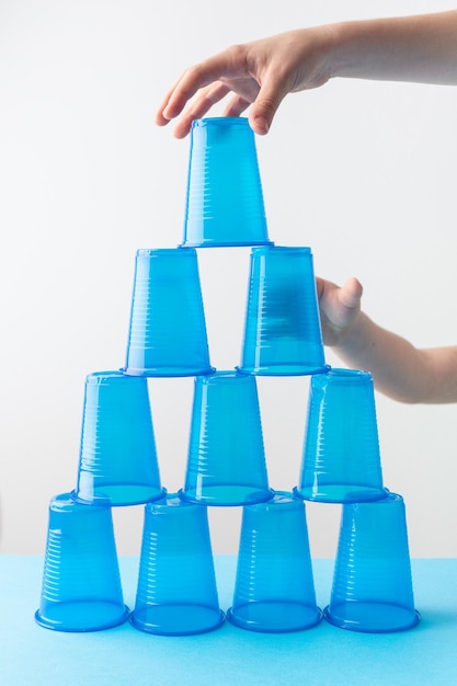 Photo pyramid of blue plastic cups set for party children hands high quality photo