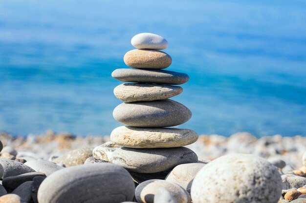 Pyramid of sea pebbles on the beach against the sea on a Sunny day