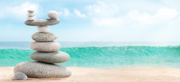 Pyramid of sea pebbles on a sunny sand beach