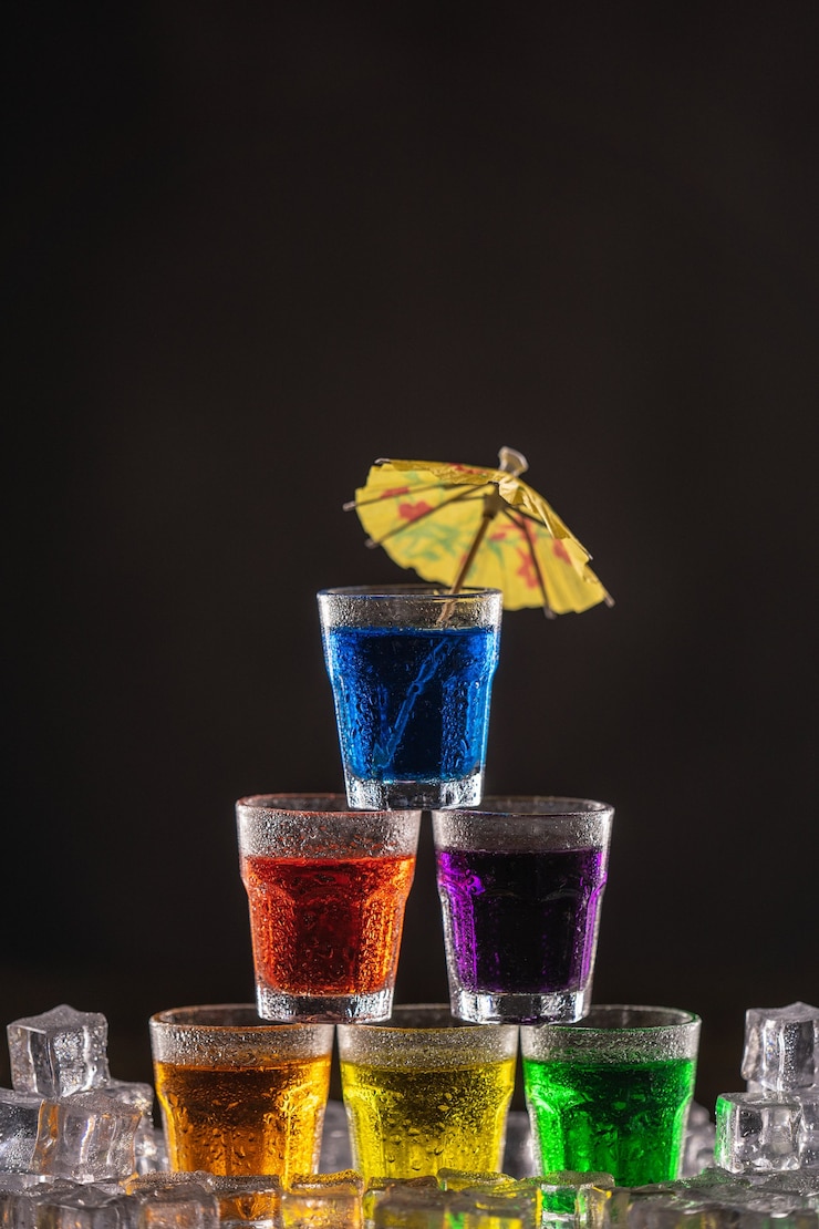 Photo カクテル用の傘で飾られた、カラフルなアルコールのショットのピラミッド