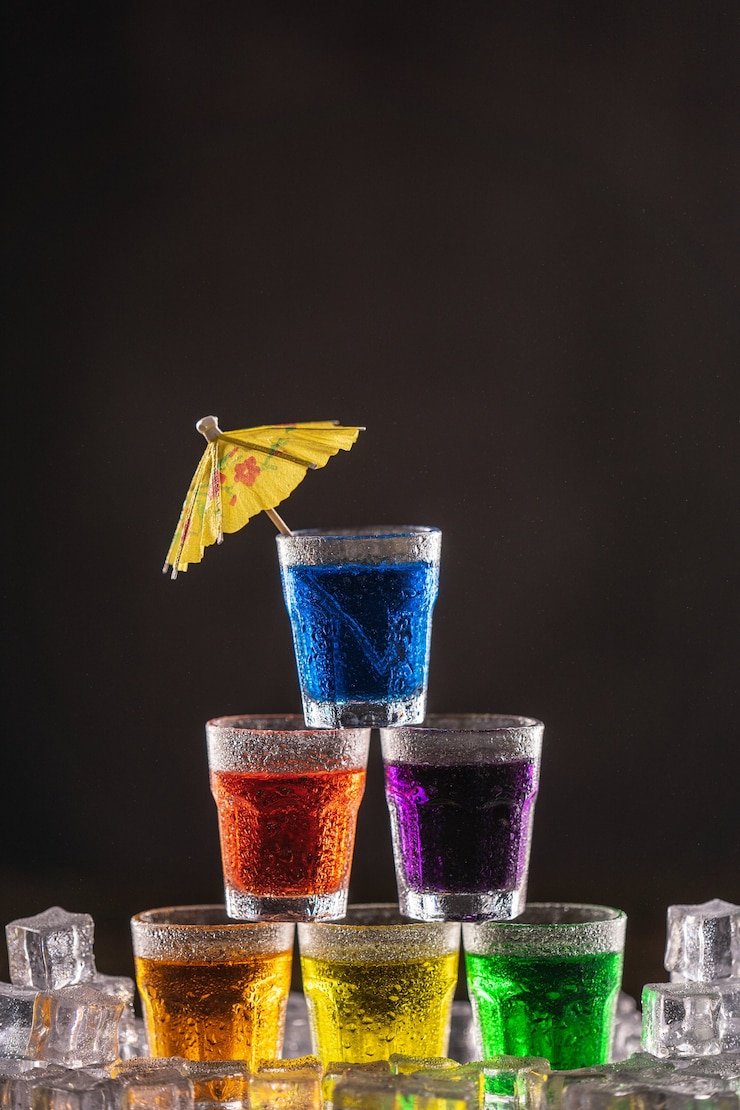 Photo カクテル用の傘で飾られた、カラフルなアルコールのショットのピラミッド