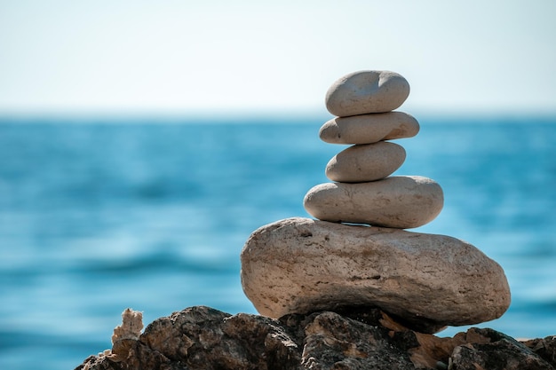 Pyramid stones on the seashore on a sunny day on the blue sea background happy holidays pebble beach