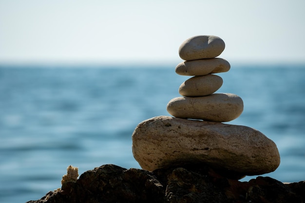 Pyramid stones on the seashore on a sunny day on the blue sea background happy holidays pebble beach