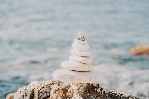 Pyramid stones on the seashore on a sunny day on the blue sea background happy holidays pebble beach