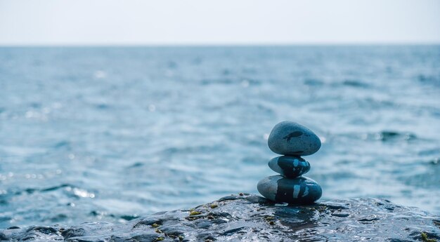 Pyramid stones on the seashore on a sunny day on the blue sea background happy holidays pebble beach