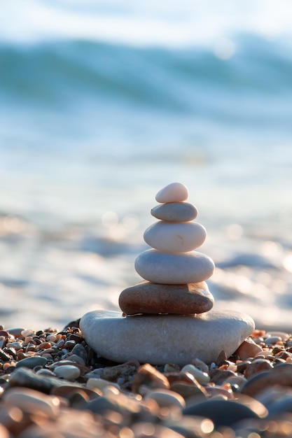 Pyramid of stones stacked on the seashore in the rays of the setting sun