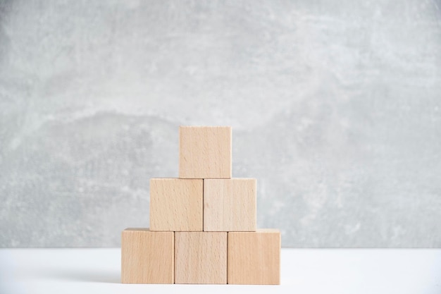 Pyramid of wooden cubes light concrete backgroundBlank blank space for text