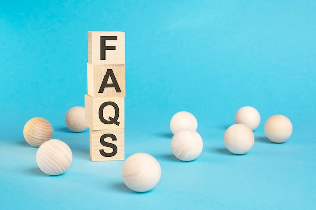 Pyramid of wooden cubes with the word FAQS and wooden balls on a blue background