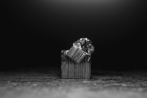 Foto un minerale di pirite illuminato dall'alto con uno sfondo nero