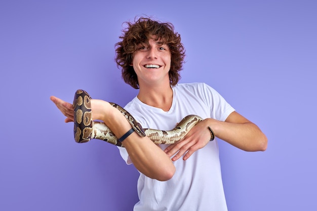 Python snake coiling around mans hand, cheerful guy enjoys, likes exotic animals