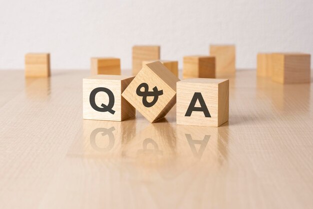 Q and A an abbreviation of wooden blocks with letters on a gray background reflection caption on the mirrored surface of the table selective focus