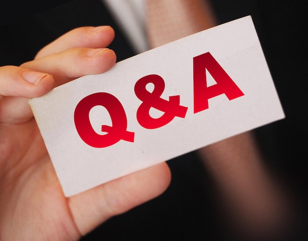 Q and A Questions and Answers sign on business card shown by a businessman Business concept