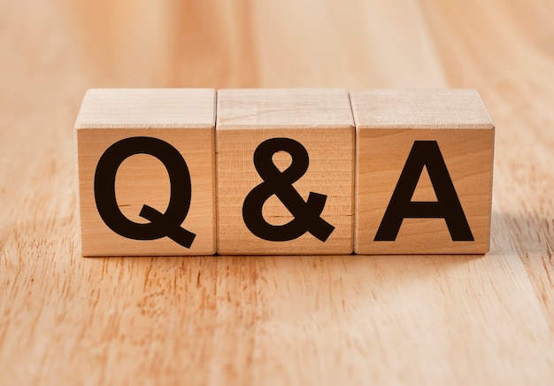 QA or Q concept in eco questions. QnA acronym on wooden cubes on wood.