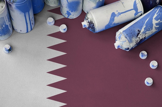 Qatar flag and few used aerosol spray cans for graffiti\
painting street art culture concept
