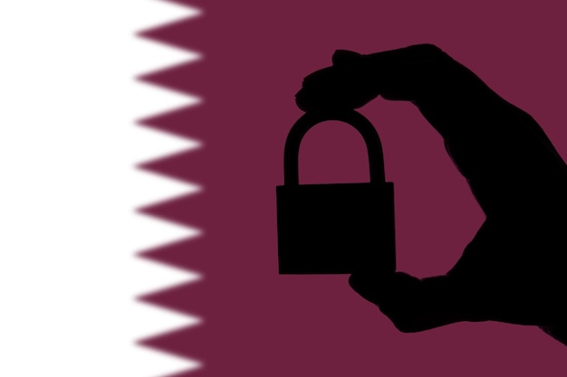 Qatar security silhouette of hand holding a padlock over\
national flag