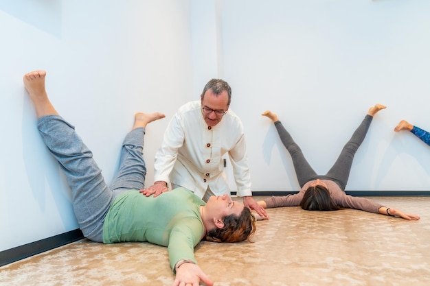 Qi gong instructeur helpt een vrouw bij het uitvoeren van een ademhalingsoefening