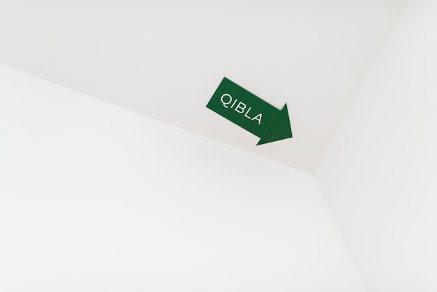 Un segno di freccia di qibla per una direzione di preghiera musulmana