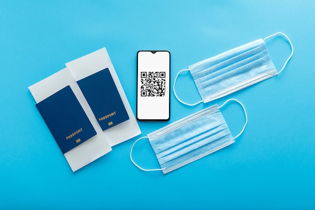 Qr code of negative covid test vaccination stamp on smartphone screen. Green pass certificate for airplane fly. Medical masks, passports plane tickets. Electronic Immunity passport tourism lockdown