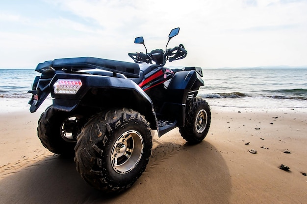 Quad staande op het strand tegen de zee